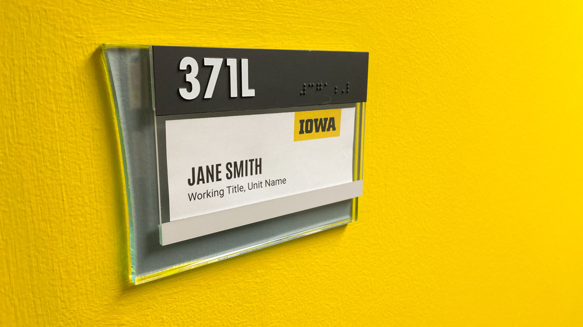 Sample name, working title, and unit name displayed in a wall mounted acrylic sign