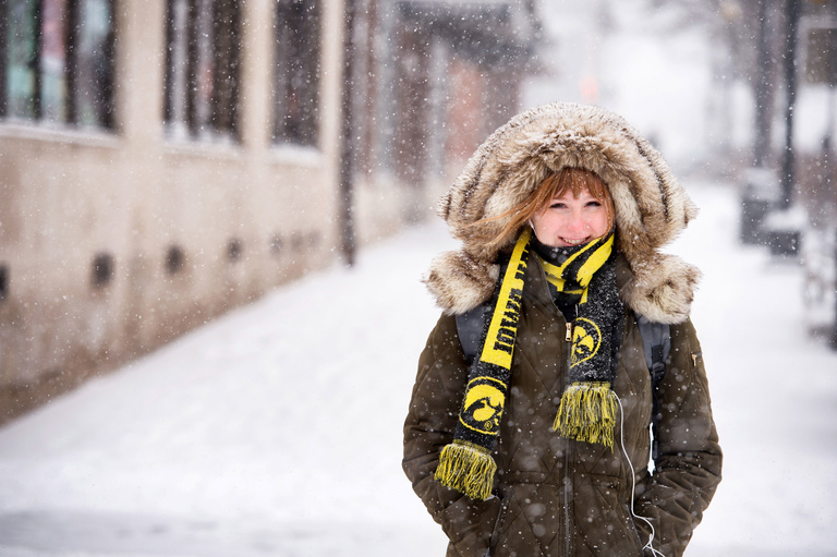 Woman bundled in snow gear and Tigerhawk scarf walking across snowy campus