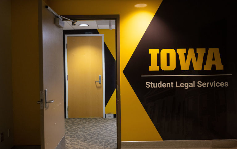 Student Legal Services lockup displayed on a black and gold wall