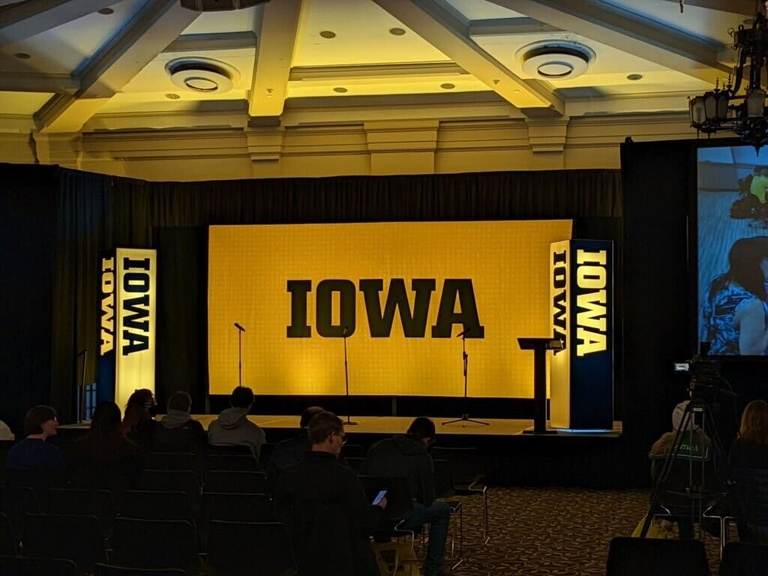 Stage design with large background displaying block IOWA logo on gold, two logo pillars flank each side of stage