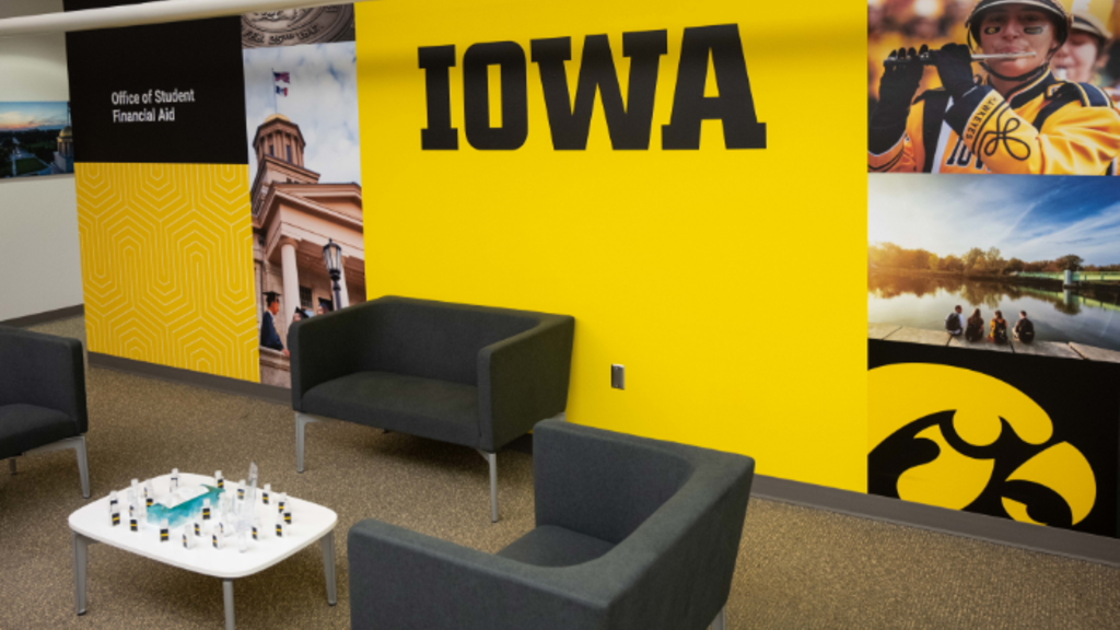Lobby area with wall of black and gold color, photography, unit identification, block IOWA logo, and Tigherawk.