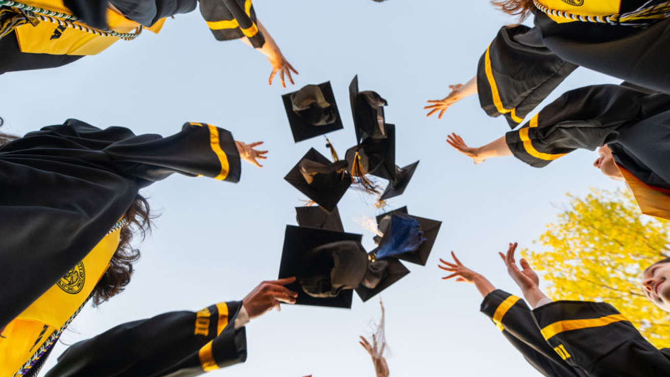 graduate students toss their caps into the air